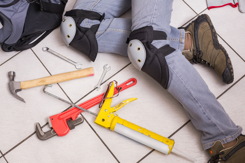 Plumber fixing under the sink in the kitchen property management company regular inspections